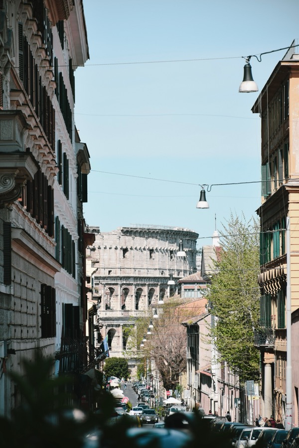 A narrow Roman street framing the Colosseum in the distance